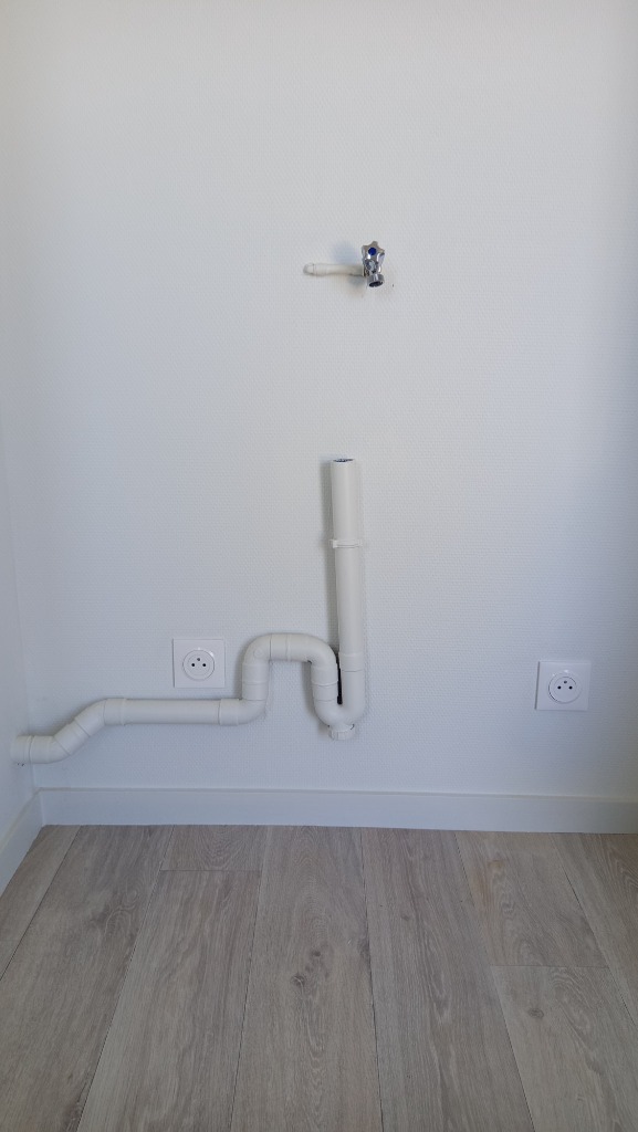 Création d'un réseau d'évacuation PVC blanc avec siphon anti-odeur et robinet d'arrivée d'eau pour machine à laver par un plombier qualifié à Lyon